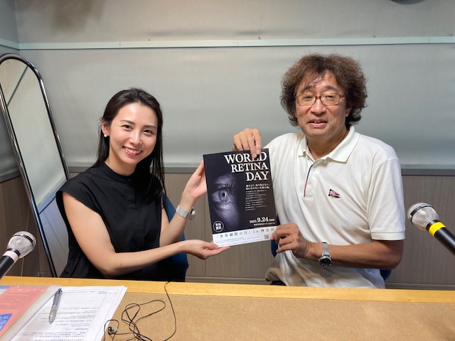 日本テレビ杉野真美アナウンサーと今村会長が世界網膜の日のチラシを掲げているところの写真です。